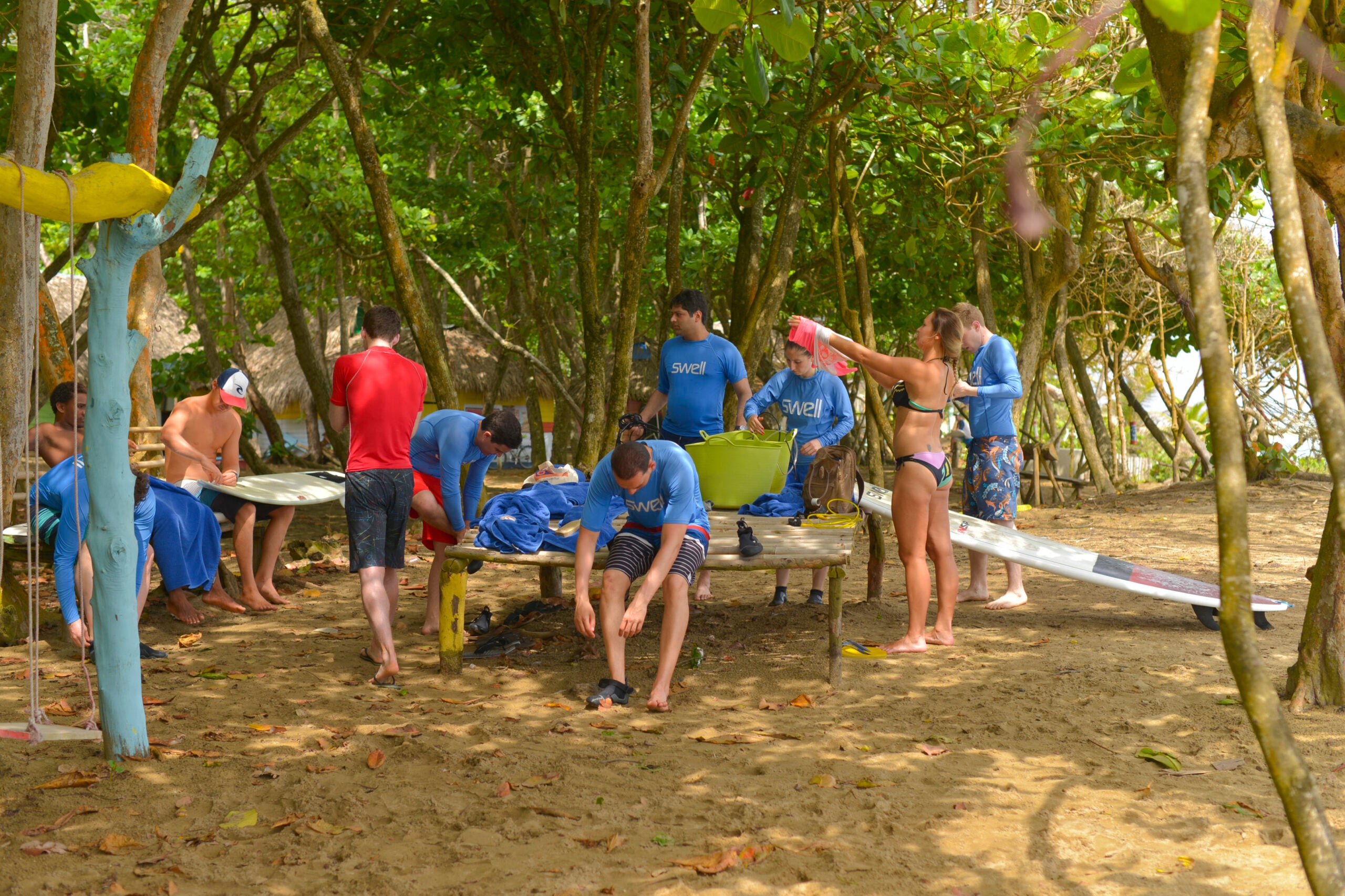 A family walking a beach path in Cabarete with surfboards, palm trees behind